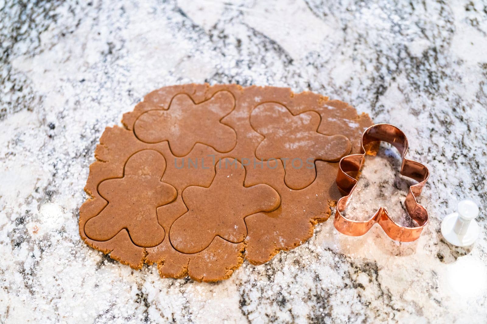 In a contemporary white kitchen, gingerbread cookie dough is skillfully rolled out, setting the stage for a delightful holiday treat.