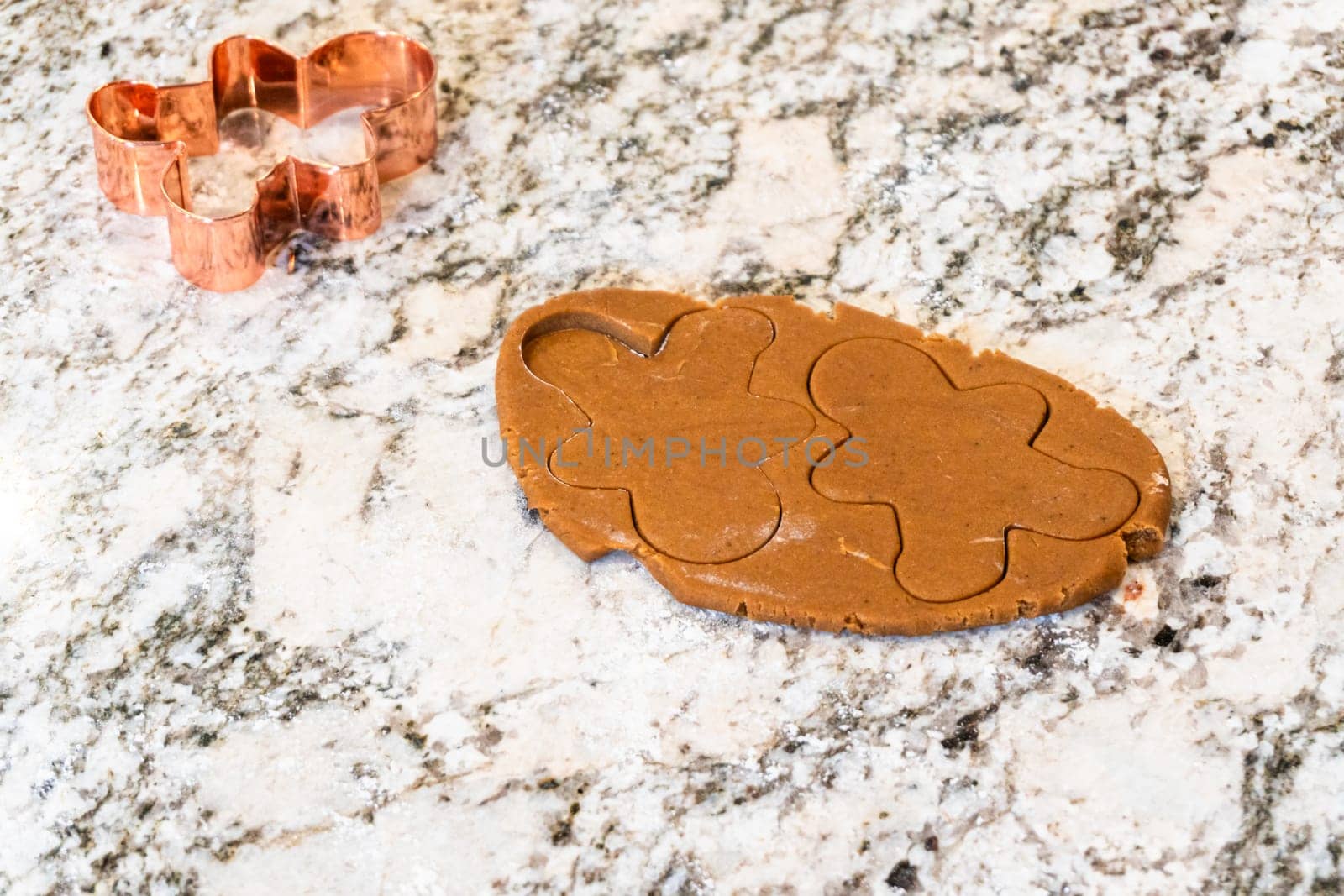 In a contemporary white kitchen, gingerbread cookie dough is skillfully rolled out, setting the stage for a delightful holiday treat.