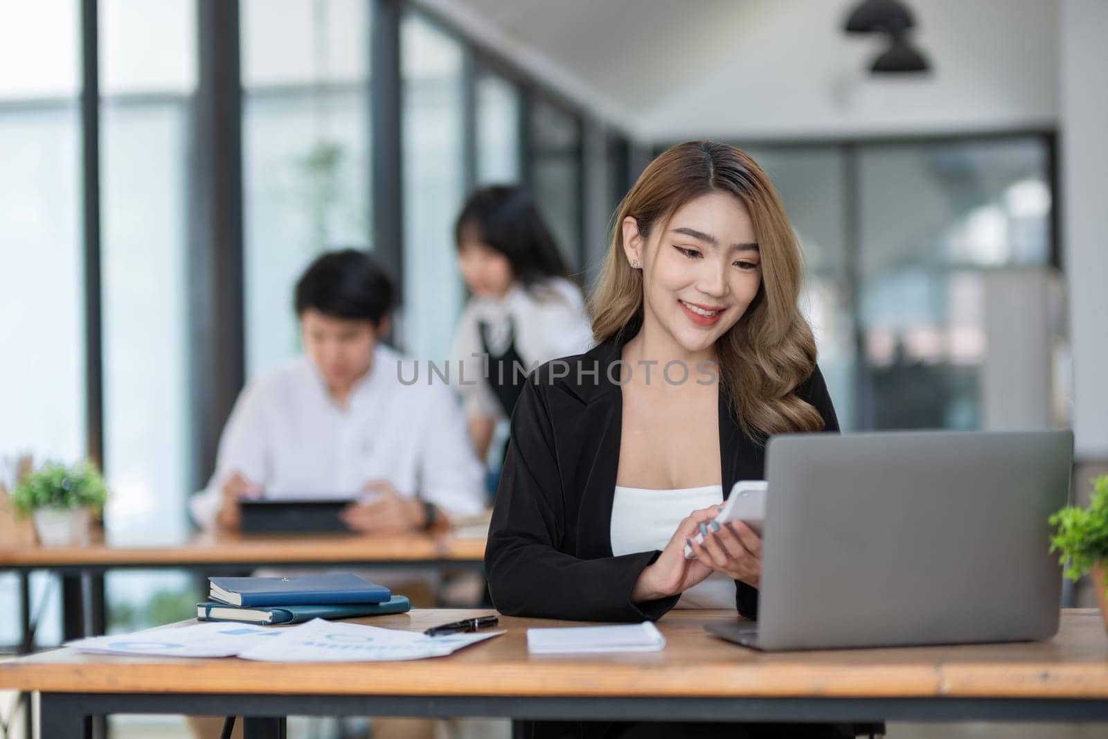 Beautiful accountant sitting with laptop calculating financial and tax figures for company on table in office room by wichayada