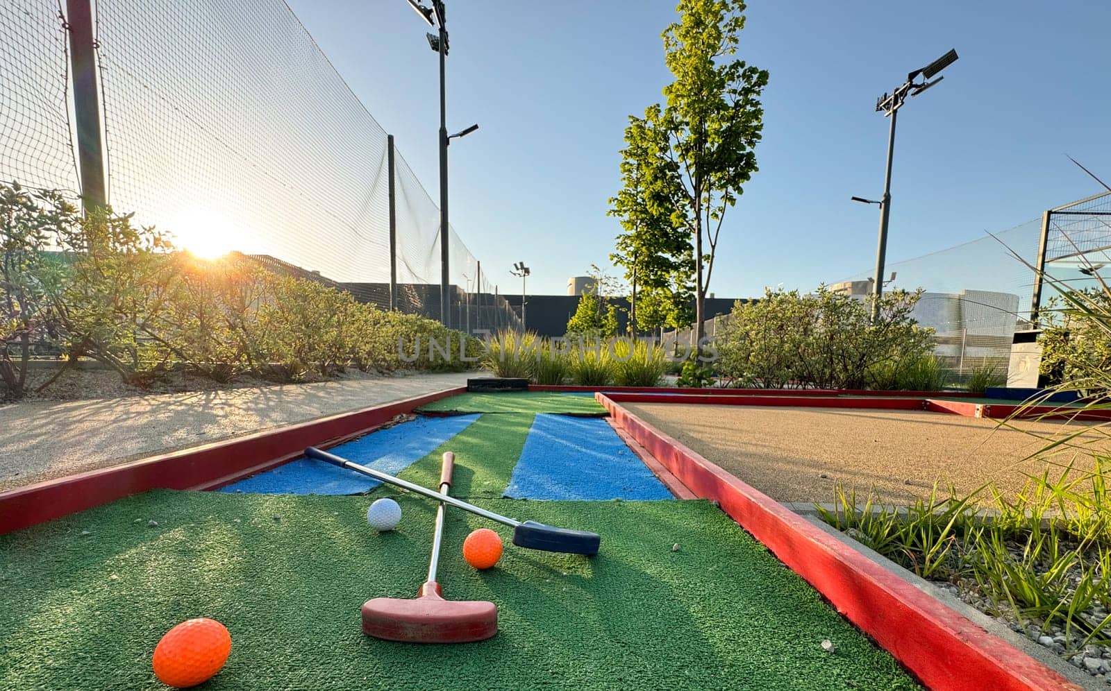 Mini-golf clubs and balls of different colors laid on artificial grass. High quality photo