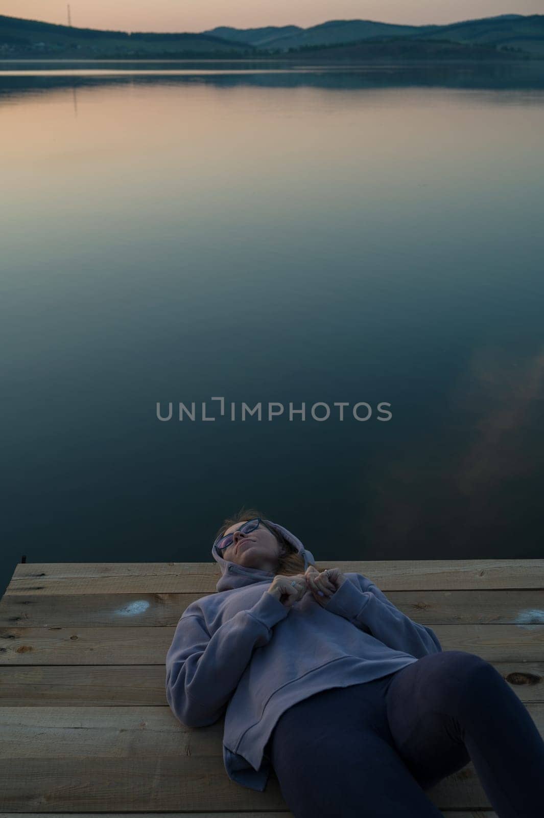 Woman lying down on the pier at lake by rusak
