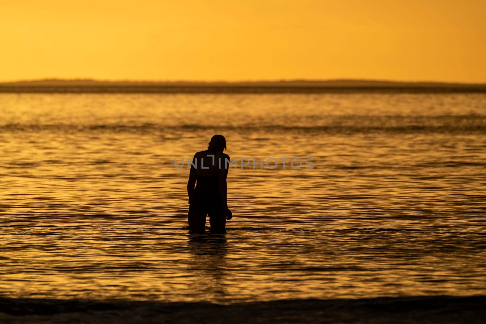 Silhouette of female swimmer going into the Atlantic ocean in Ireland.