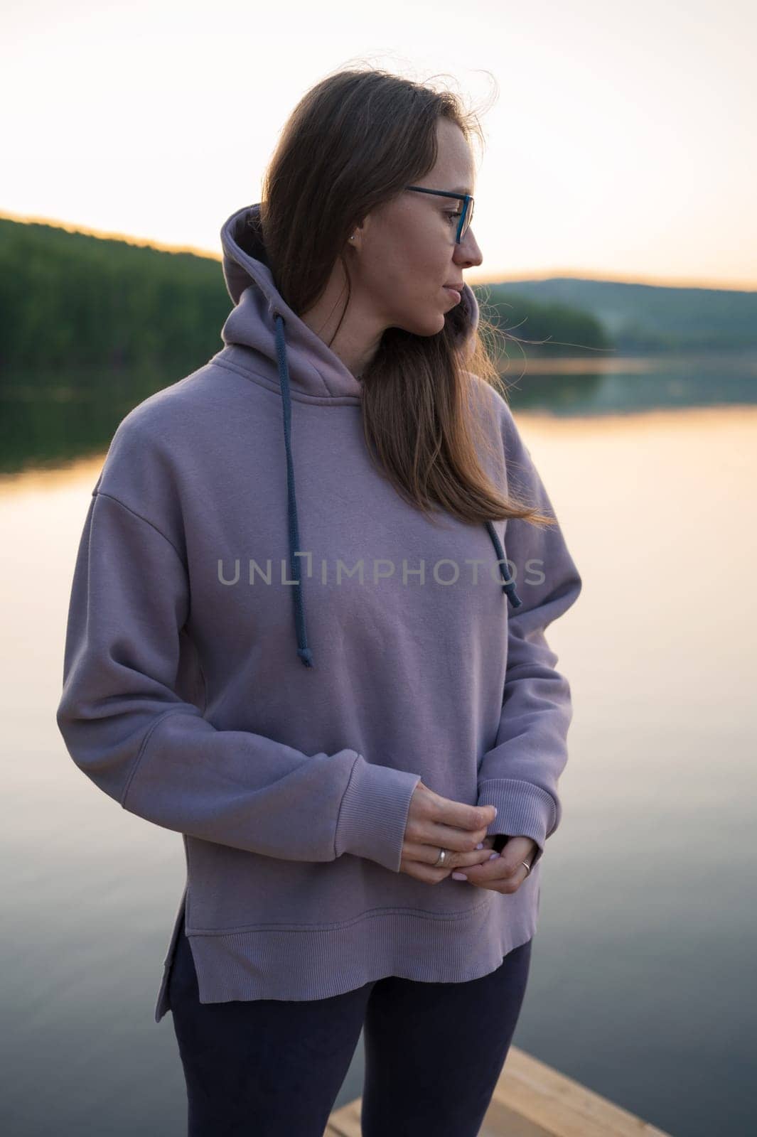 Woman sitting on the pier, closeup portrait, summer sunset