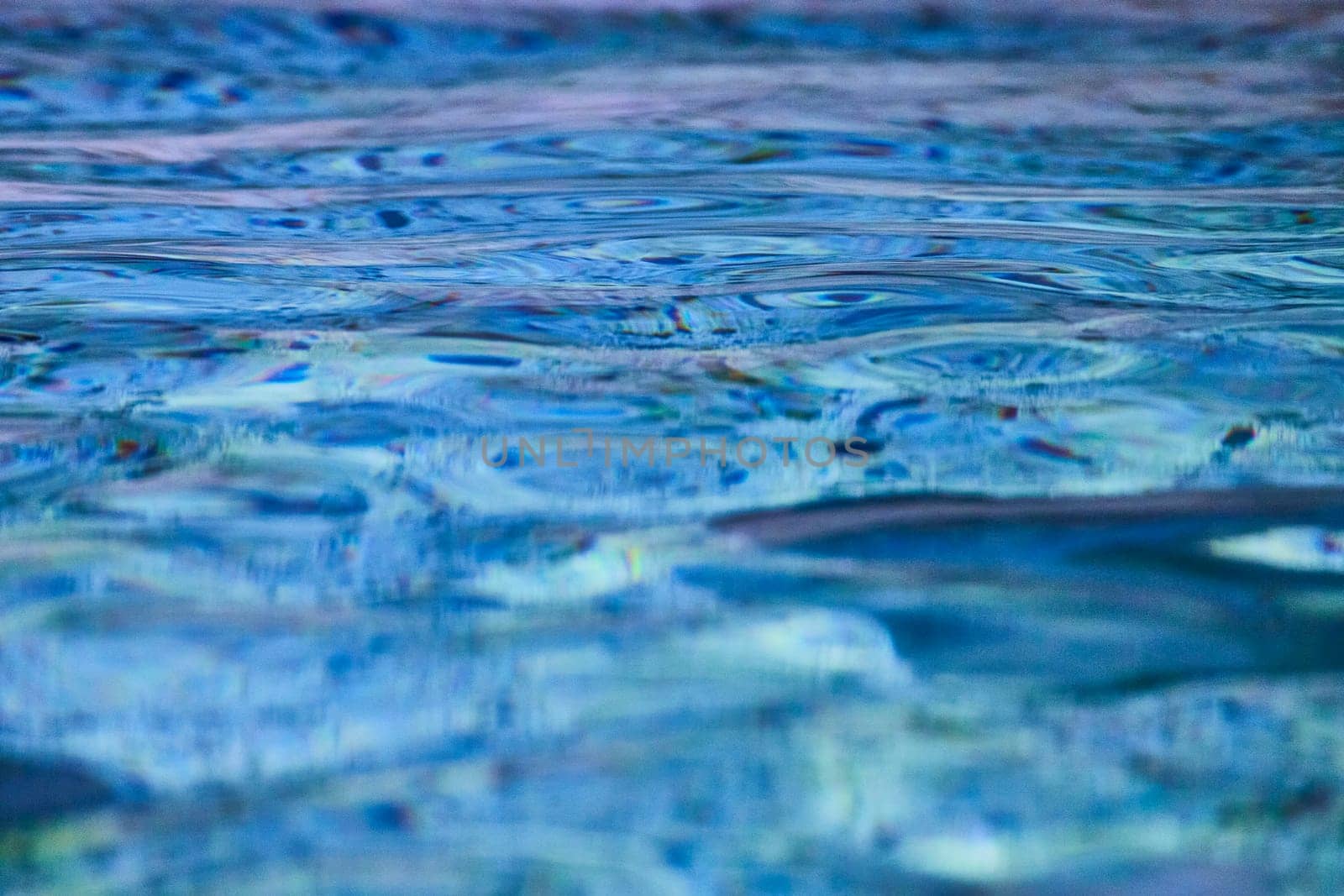 Vibrant water ripples in close-up, showcasing nature's palette of blues and greens with a hint of dynamic light.