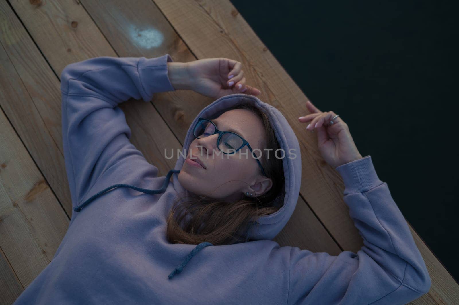 Woman lying down on the pier at lake, closeup portrait, summer sunset