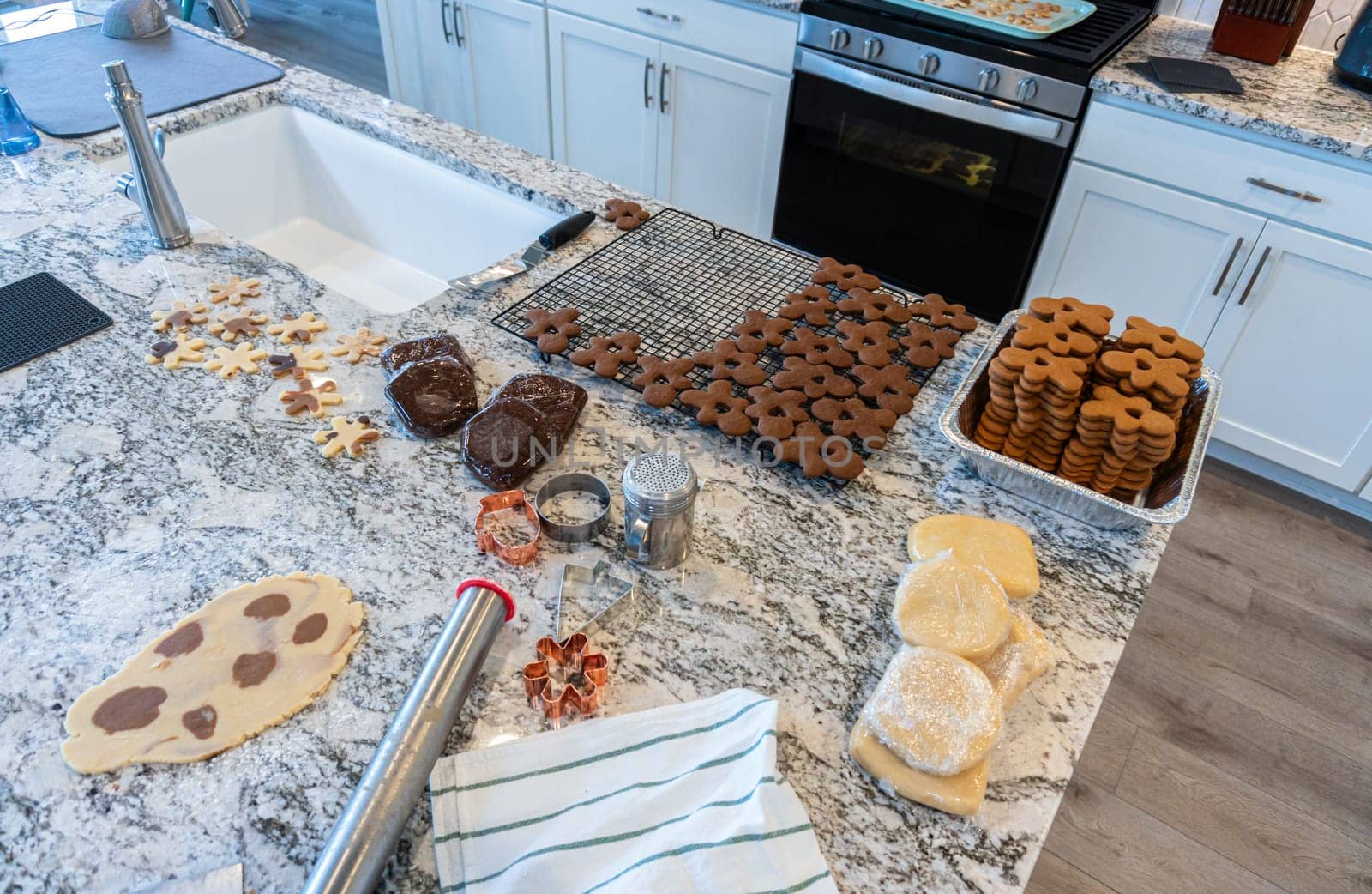 In a contemporary white kitchen, gingerbread cookie dough is skillfully rolled out, setting the stage for a delightful holiday treat.