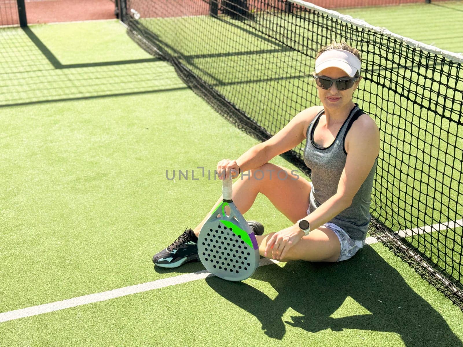 Portrait of active emotional woman playing padel tennis on open court in summer, swinging racket to return ball over net .. High quality photo