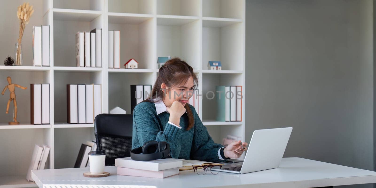 Young woman working on a laptop at a home office desk.