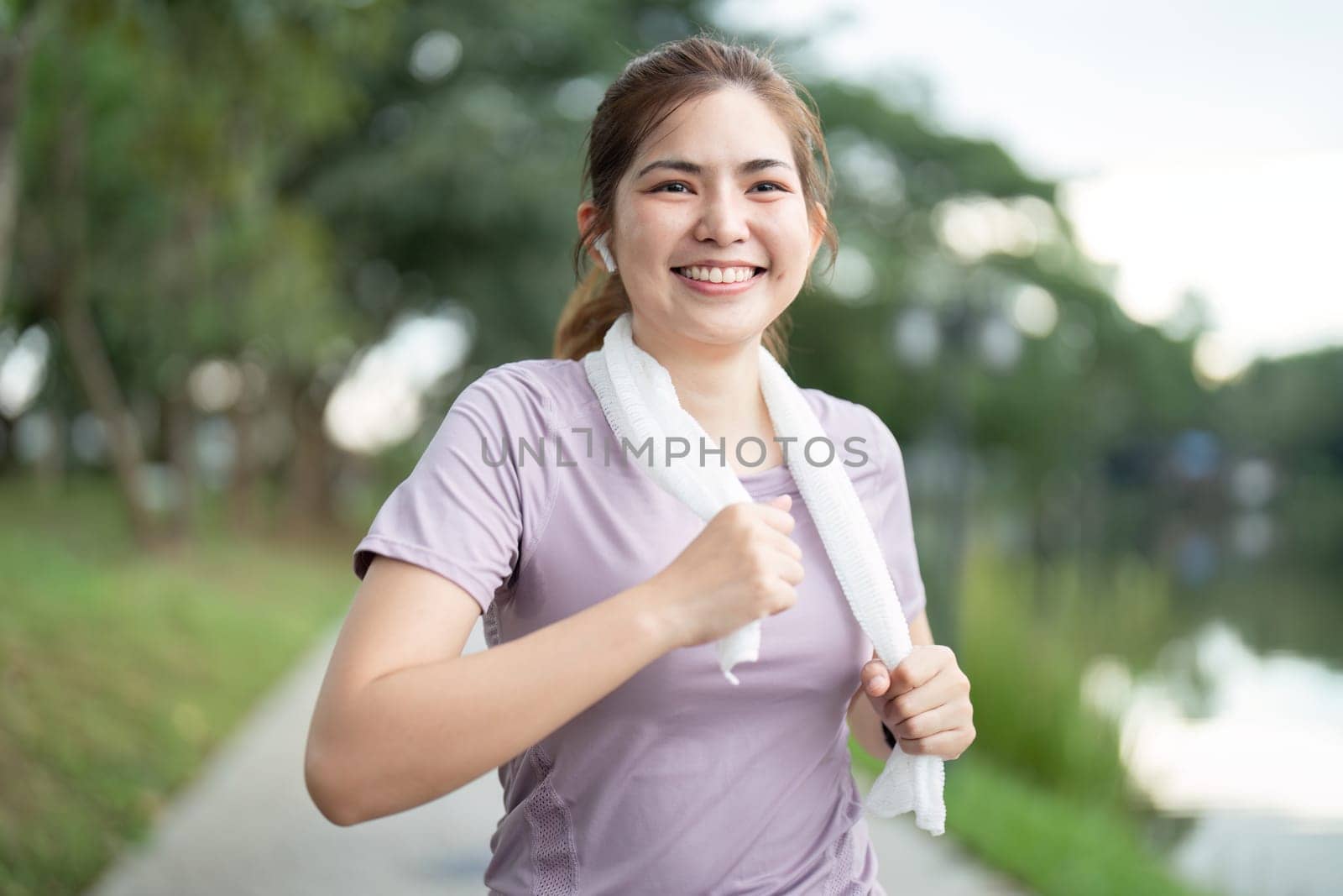 Asian fitness female sportswoman runner doing morning jogging exercise training outdoor. Happy smile woman asian running in the park by nateemee