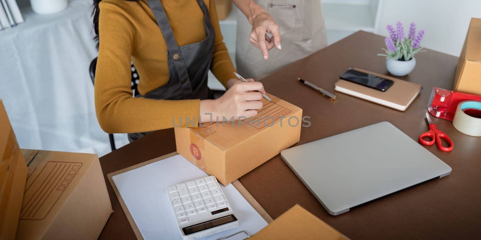 Close up of women preparing packages in a small business office.