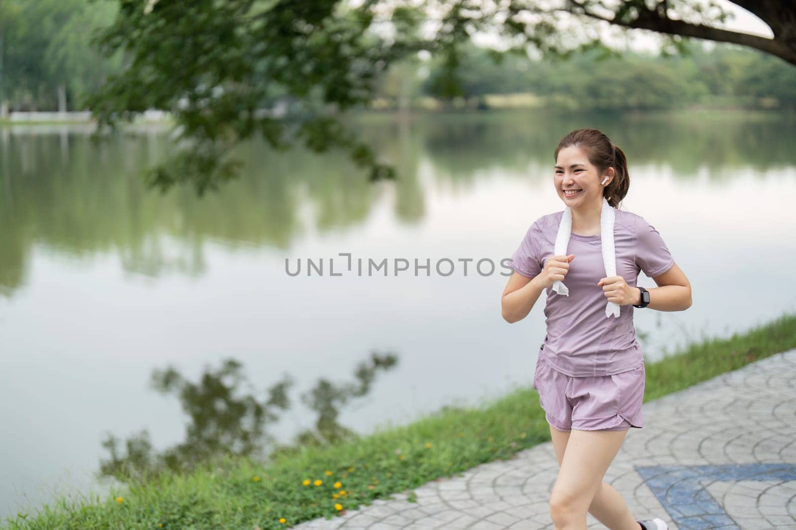 Young asian woman enjoying a morning run in a park. Workout exercise in the morning. Healthy and active lifestyle concept.