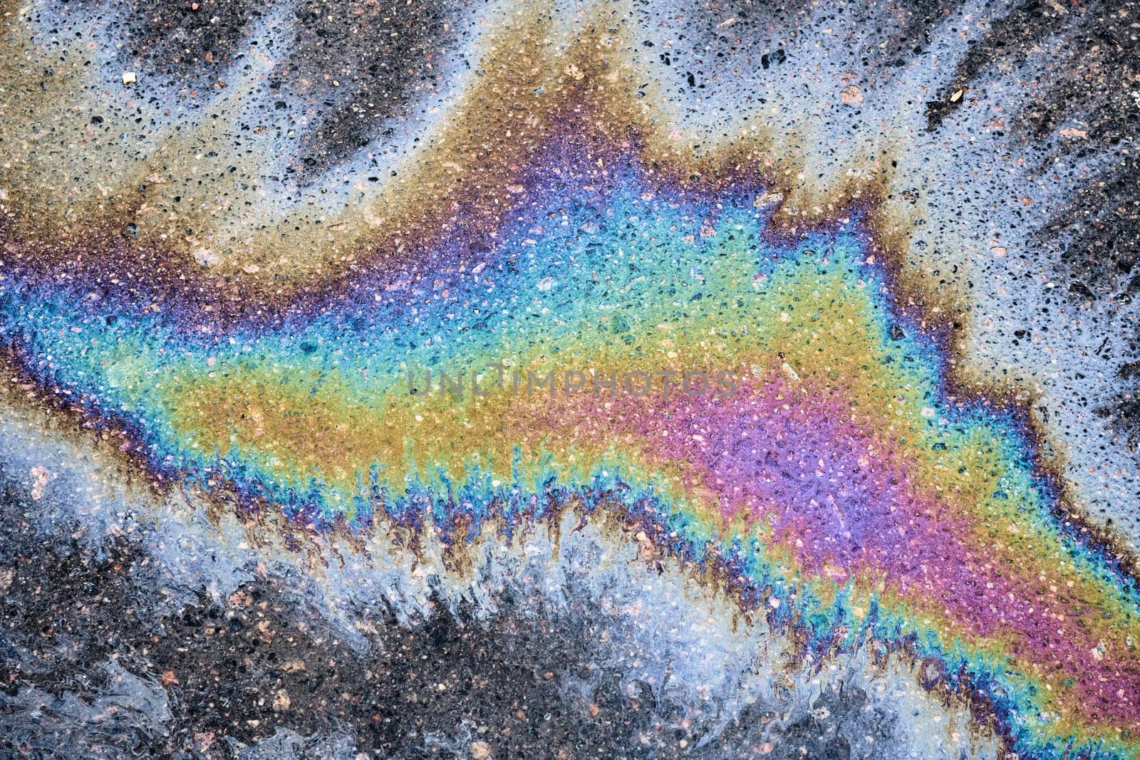 Background texture of oil spill on dark asphalt, parking lot.