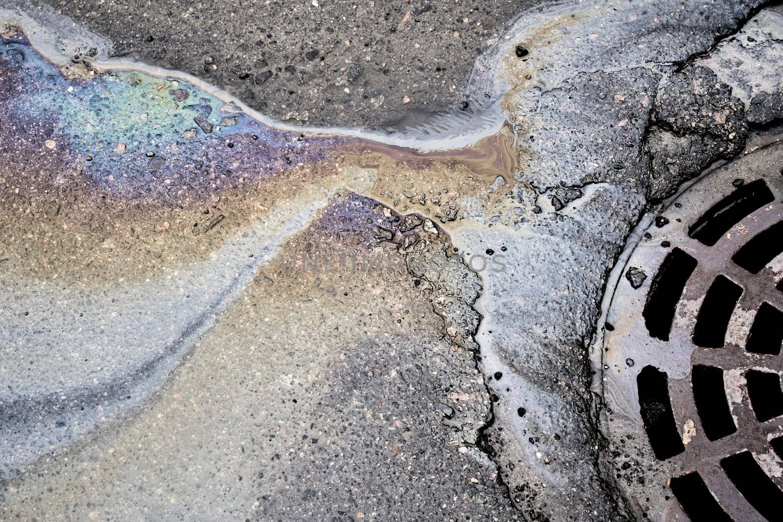 Oil stain on the asphalt surface seeps into the storm drainage system