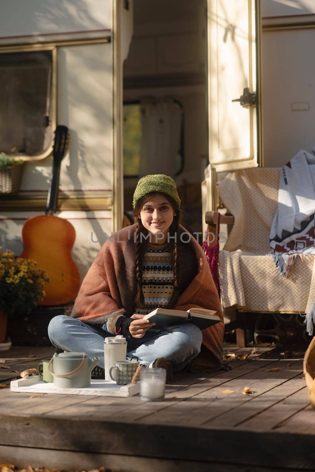 A chic, modern hippie woman indulges in a warm beverage on the terrace, exuding style. High quality photo