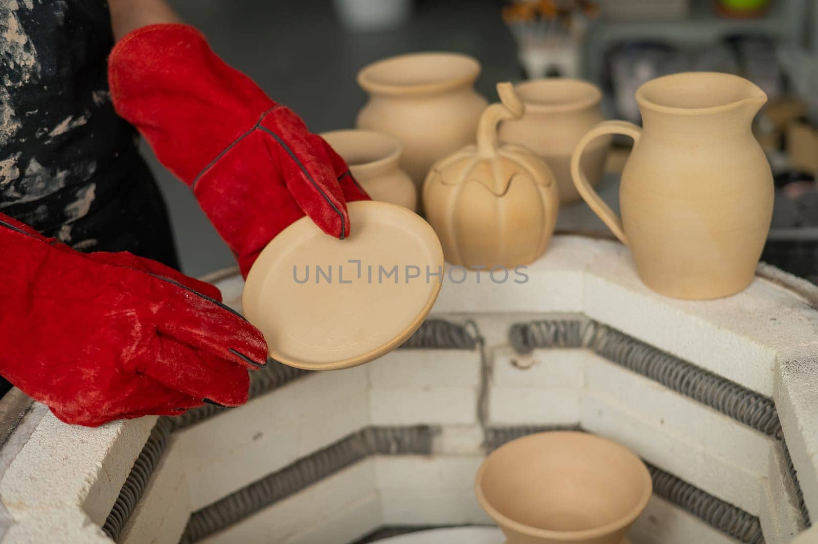 Close-up of a man's hands loading ceramics into a special kiln