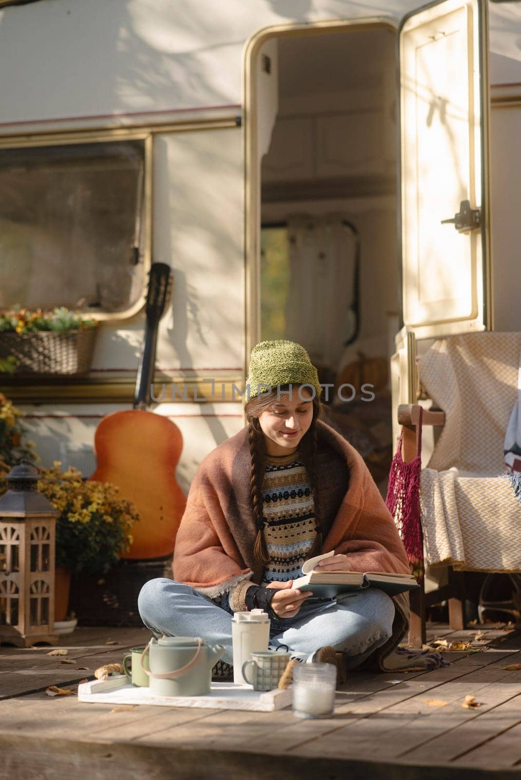 A hip, young lady in a boho-chic attire enjoys a steaming drink on the terrace. High quality photo