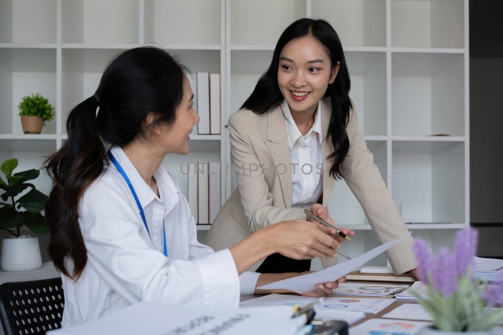 Team businesswomen discussing financial reports in office by wichayada