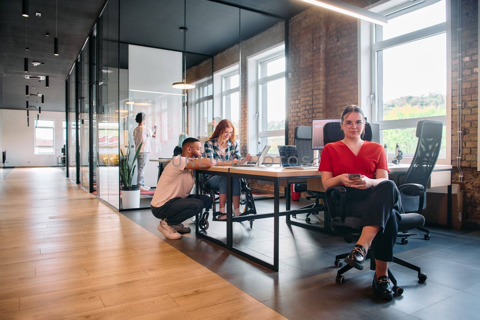 A diverse group of business professionals collaborates in a modern startup coworking center, utilizing a mix of paper-based and technological tools such as mobile phones and computers .