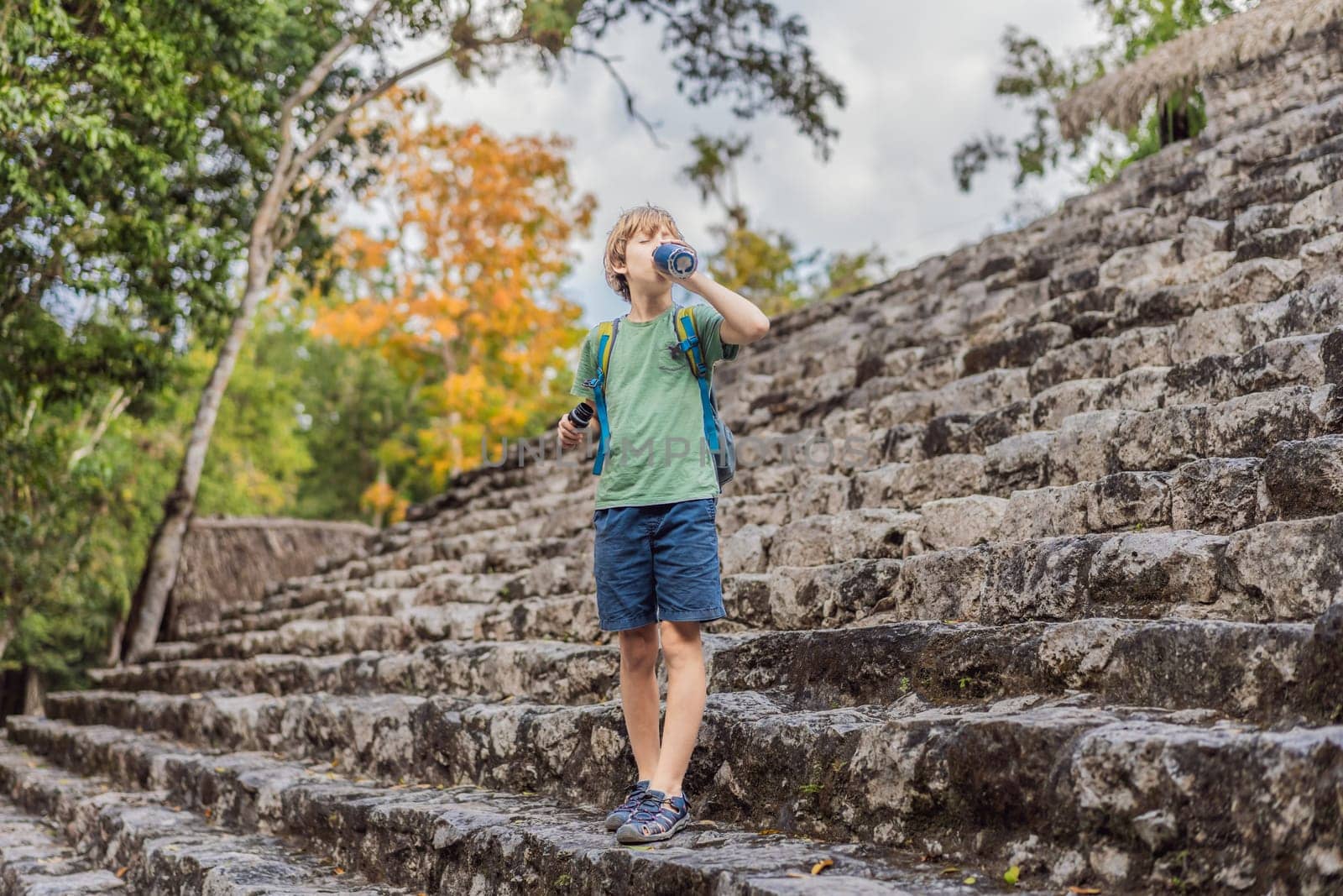 Boy tourist at Coba, Mexico. Ancient mayan city in Mexico. Coba is an archaeological area and a famous landmark of Yucatan Peninsula. Cloudy sky over a pyramid in Mexico.
