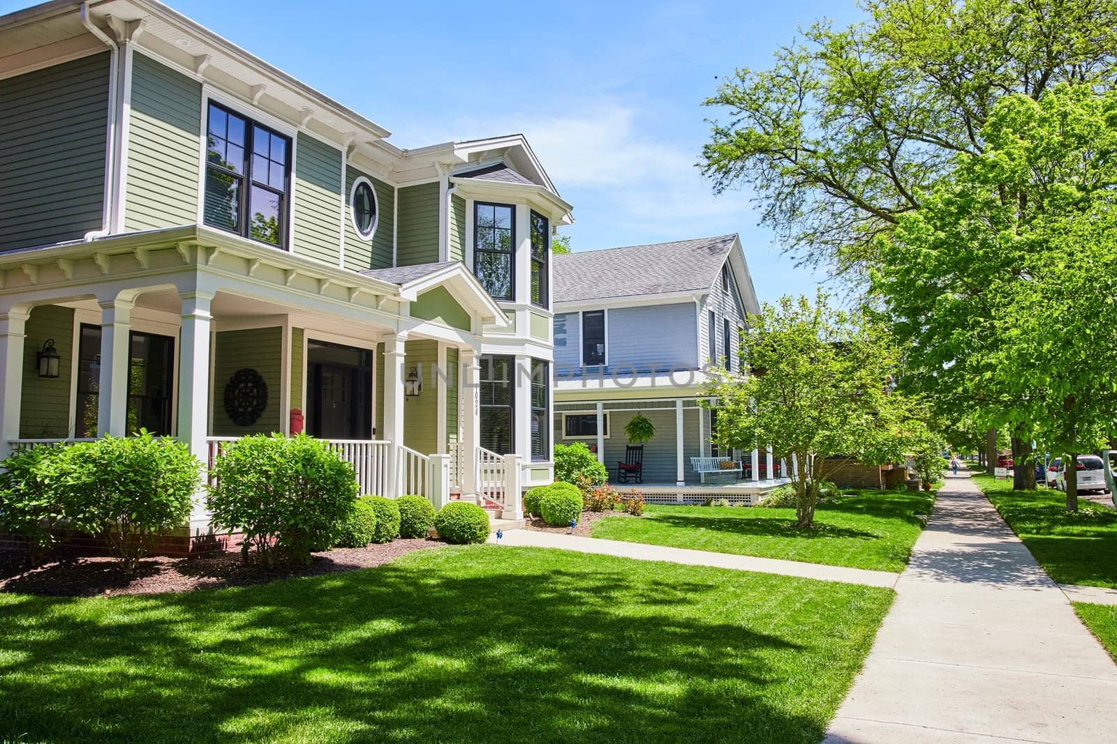 Elegant suburban homes in Fort Wayne, Indiana, showcasing lush lawns and cozy porches under a clear blue sky.