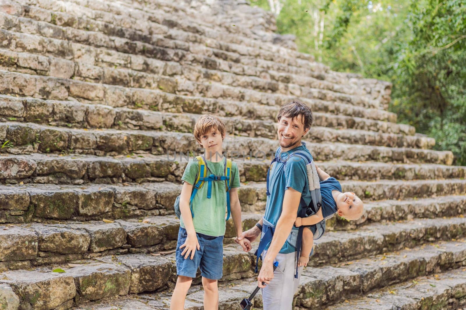 Dad with two sons tourists at Coba, Mexico. Ancient mayan city in Mexico. Coba is an archaeological area and a famous landmark of Yucatan Peninsula. Cloudy sky over a pyramid in Mexico by galitskaya