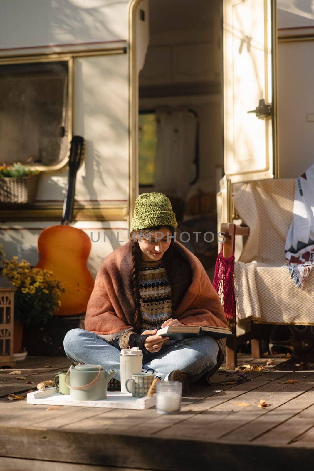 A trendy, hippie-inspired girl relishes a hot beverage on the house terrace, showcasing her style. High quality photo