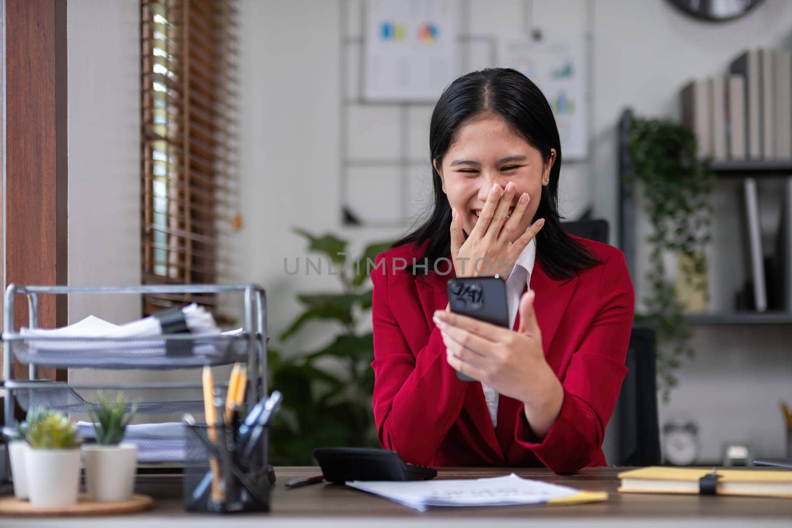 Beautiful accountant talking on the phone and calculating financial figures and calculating taxes for the company. by wichayada