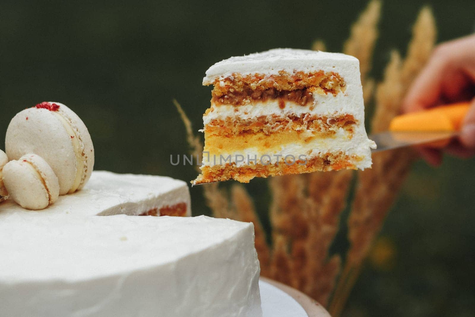 A person gently cuts a piece of cake with a knife.