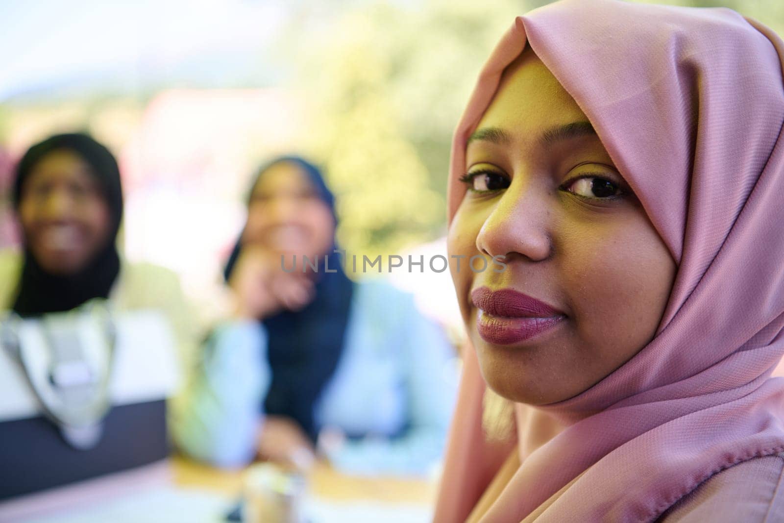 A Middle Eastern girl wearing a hijab, with a bright smile and a pink headscarf, captured in a close-up portrait exuding joy and positivity.