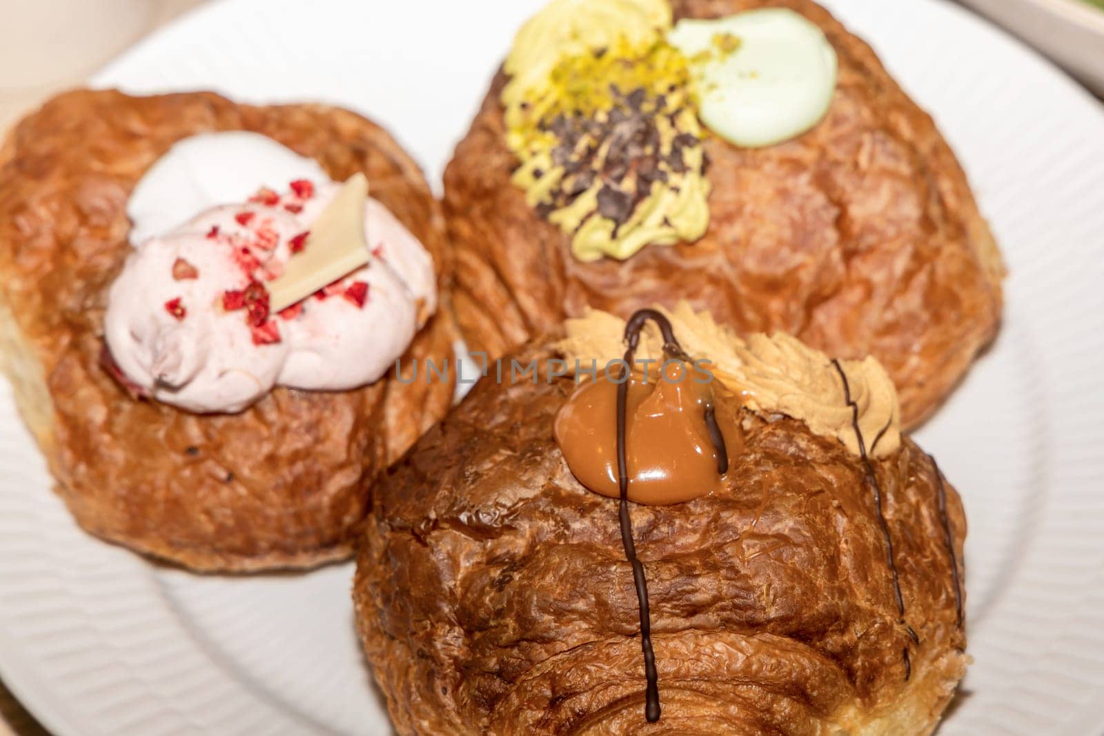 Delicious Mardi Gras buns with cream on a white plate.