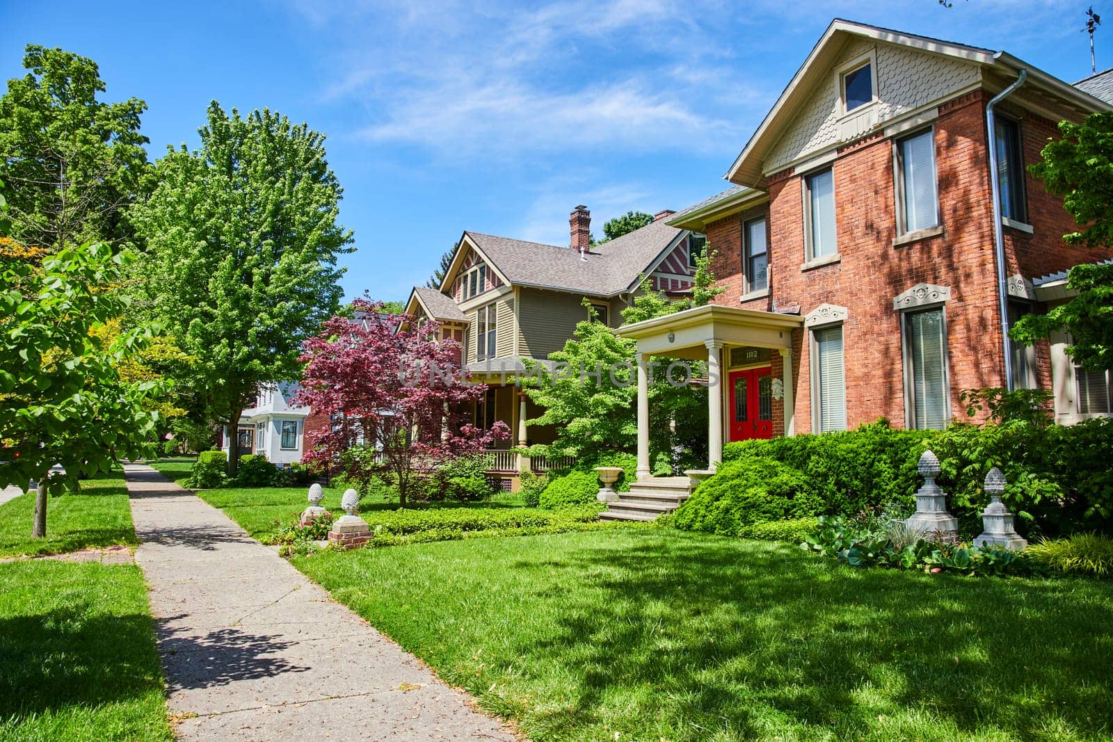 Charming homes in Fort Wayne: Victorian elegance meets modern craft on a sunny suburban street.