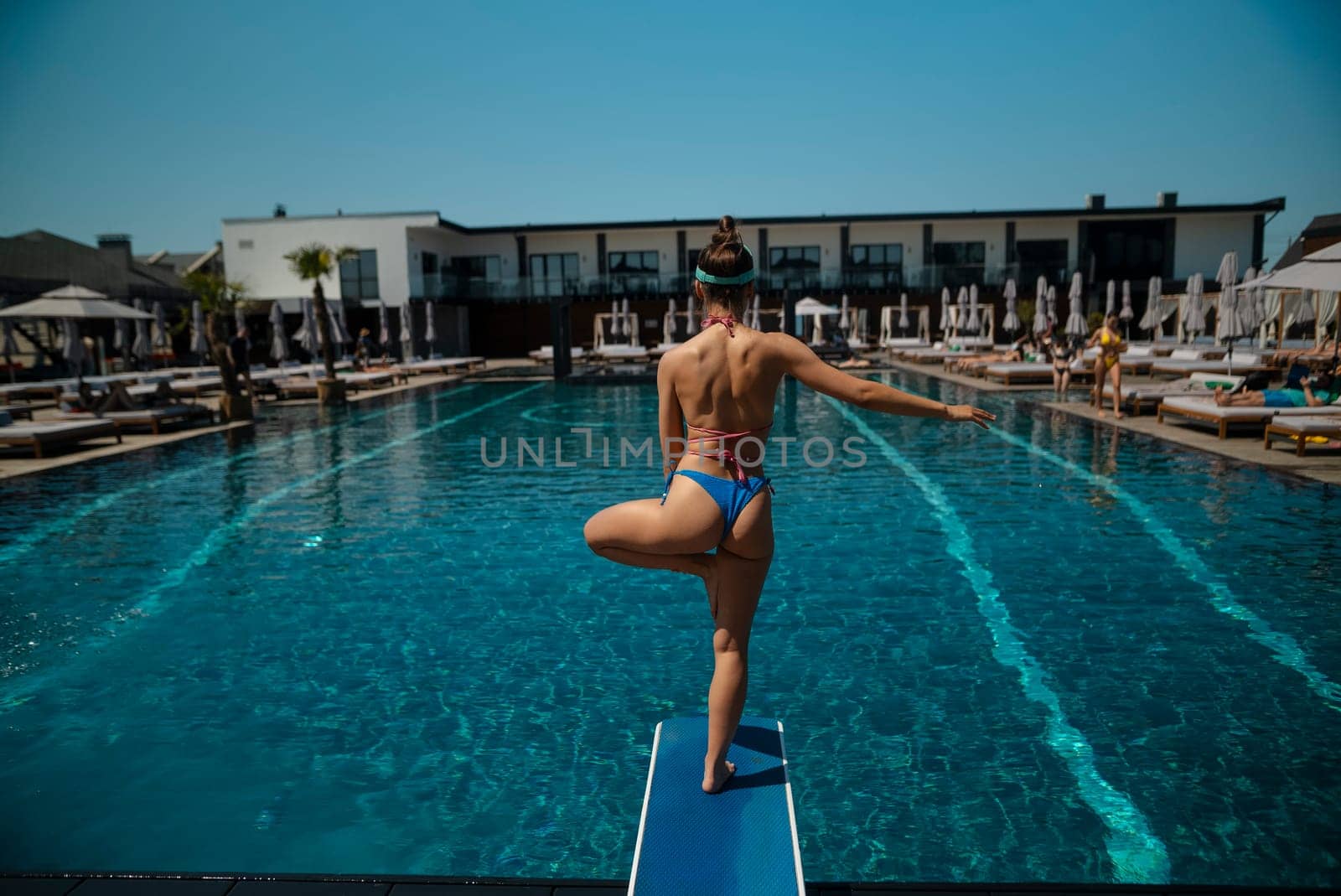 A radiant young woman with a stunning physique poses gracefully by the pool in her bikini. High quality photo