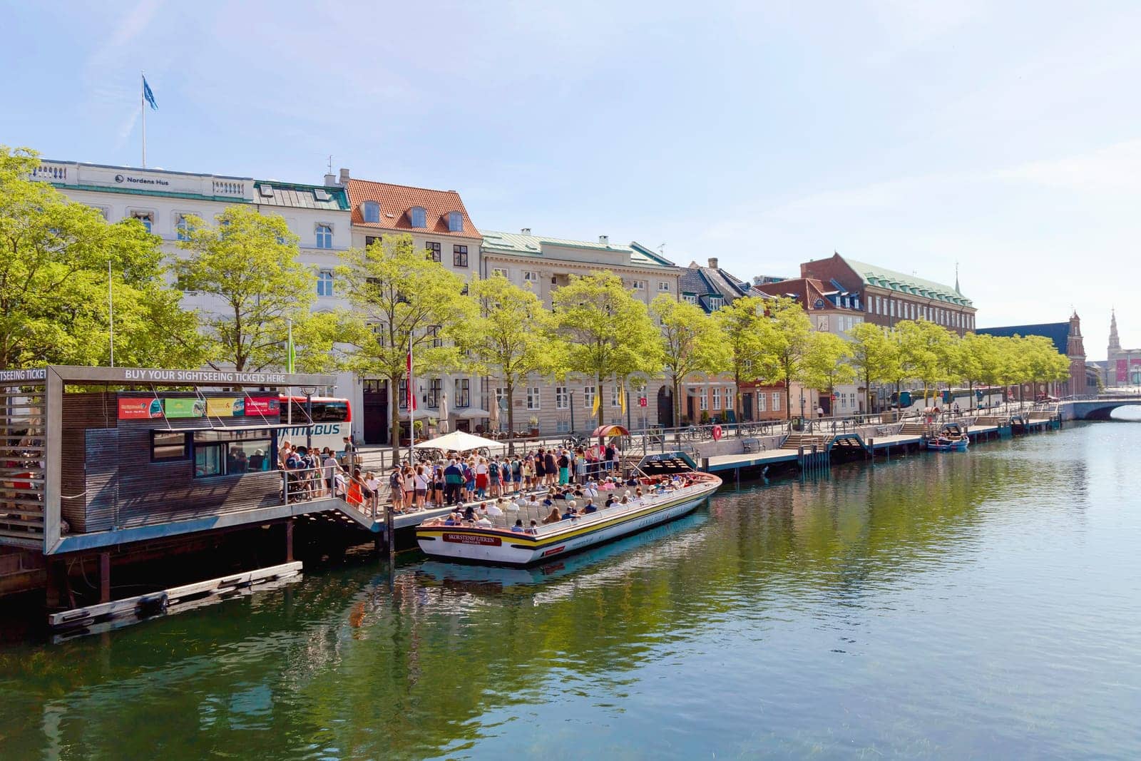 A boat with people is sailing along a water canal in the city. Copenhagen, Denmark - November 17, 2023
