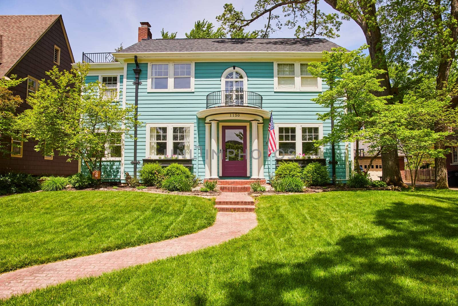 Charming turquoise home with a purple door and American flag, nestled in Fort Wayne's historic South Wayne district.