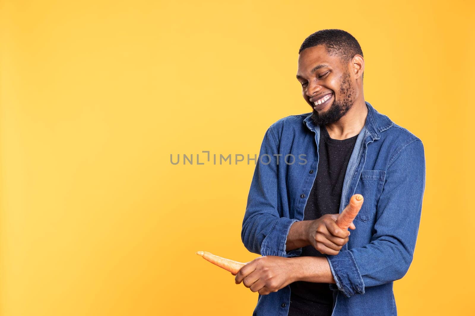 African american male model enjoys playing with carrots by DCStudio