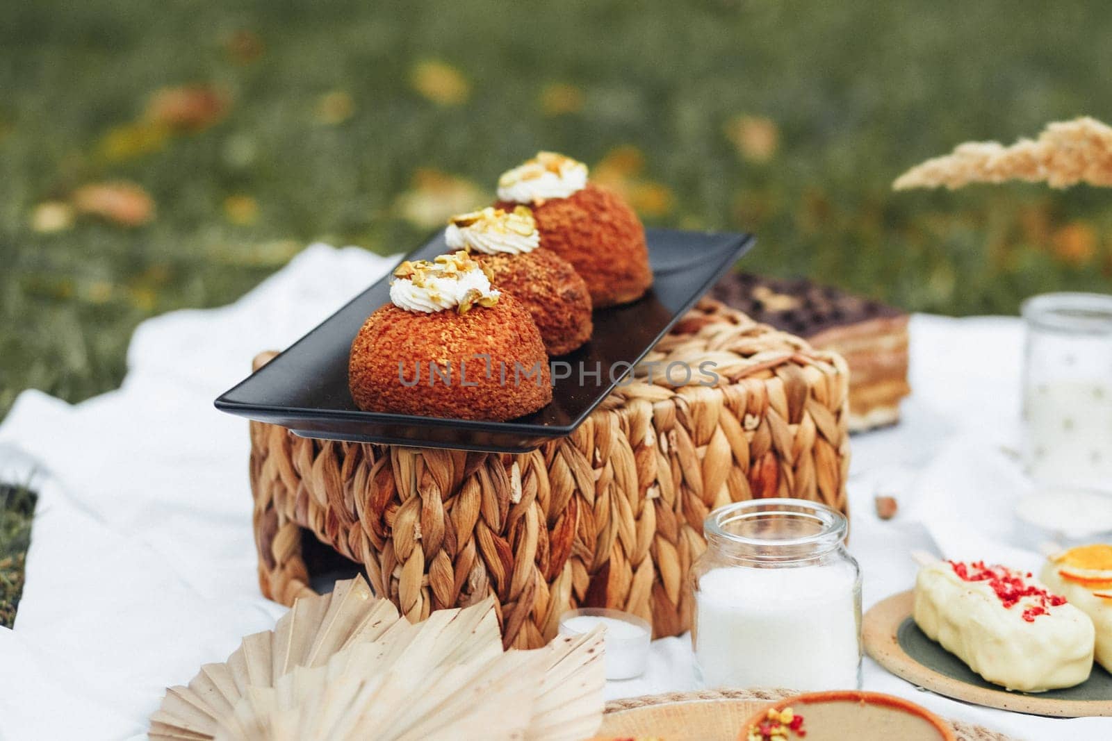 A colorful picnic table adorned with an array of delectable desserts and refreshing drinks under the sunlight.