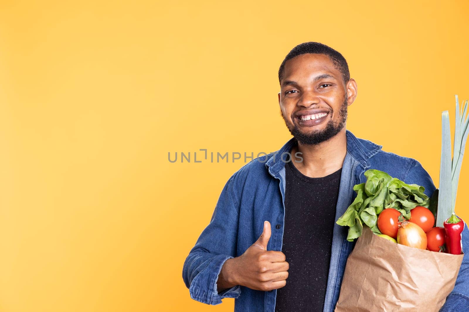 Charismatic friendly guy shows like gesture in studio, giving a thumbs up for fresh homegrown produce. Cheerful man recommending local farmers market for healthy eating, agreement.