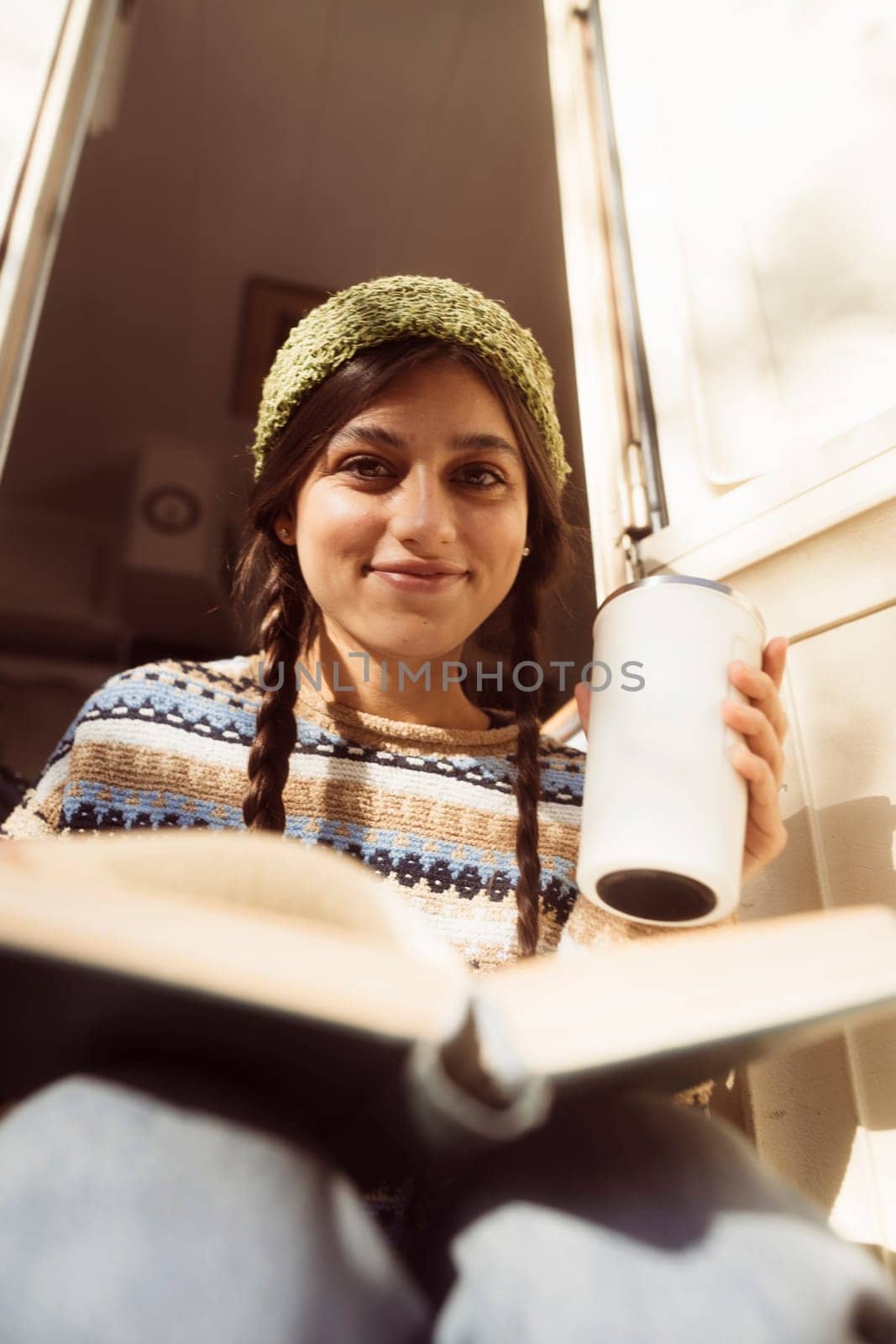 A trendy woman showcases her hippie-inspired fashion against the scenic park view, with a trailer in the background. High quality photo