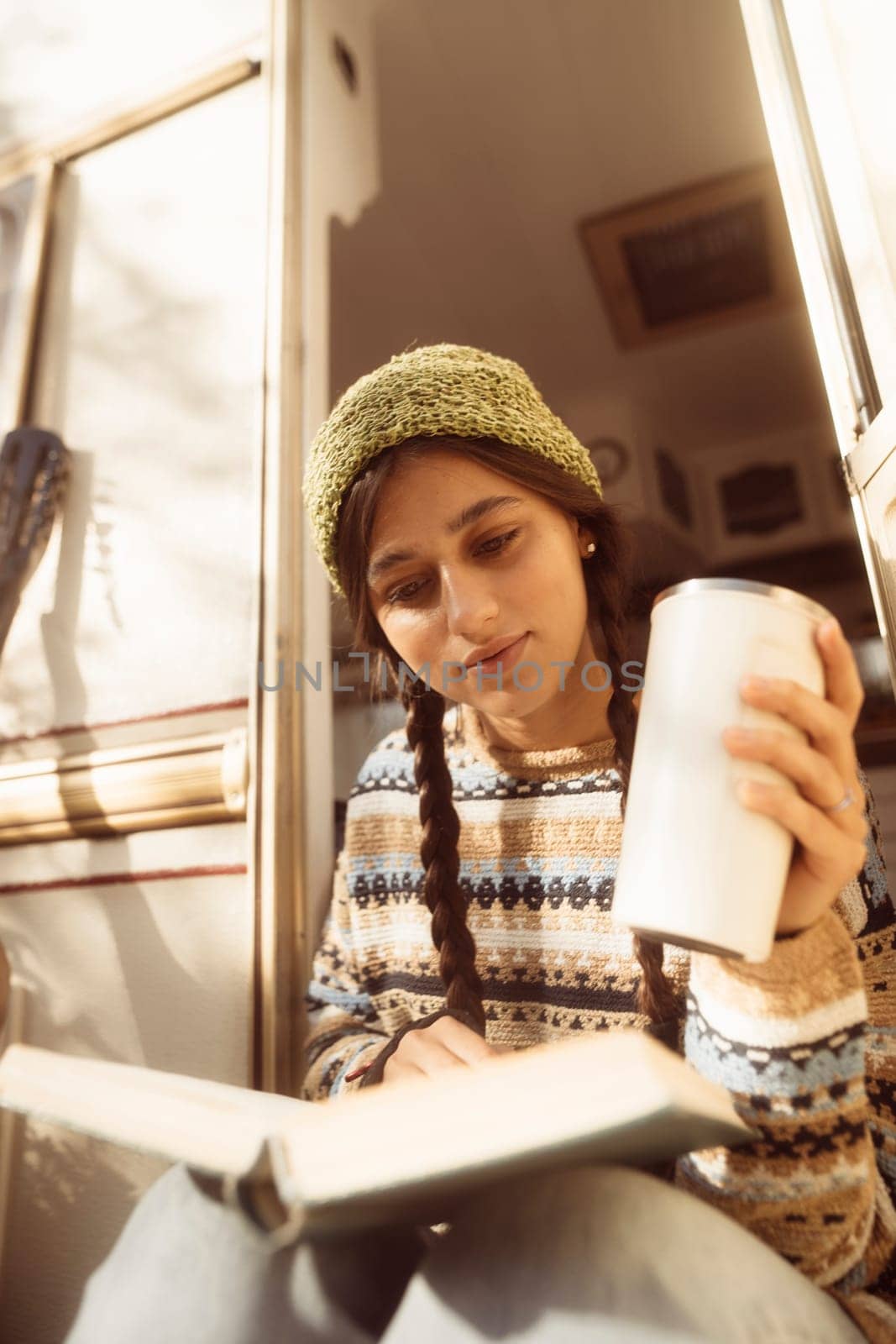 A fashionable, contemporary hippie woman takes a moment to enjoy a hot drink on the terrace. High quality photo