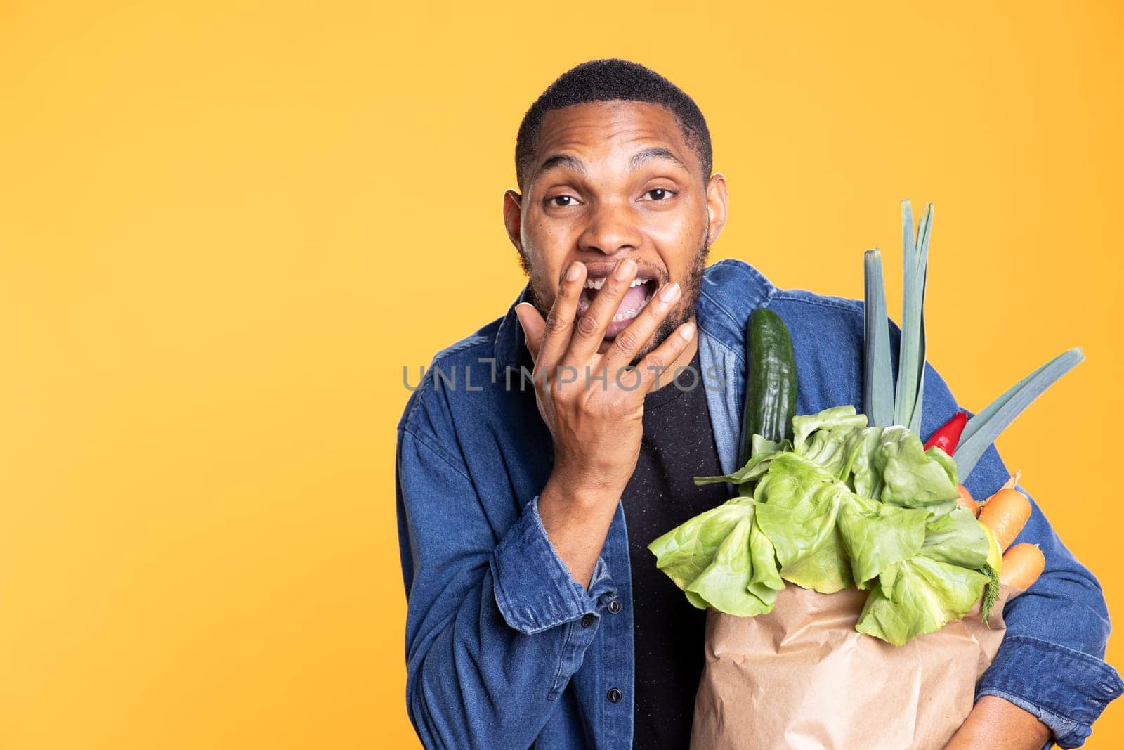 Joyful positive model feeling satisfied with fresh groceries in a paper bag, supporting vegan nutrition and ethically sourced food. Optimistic bio enthusiast enjoys natural organic veggies.