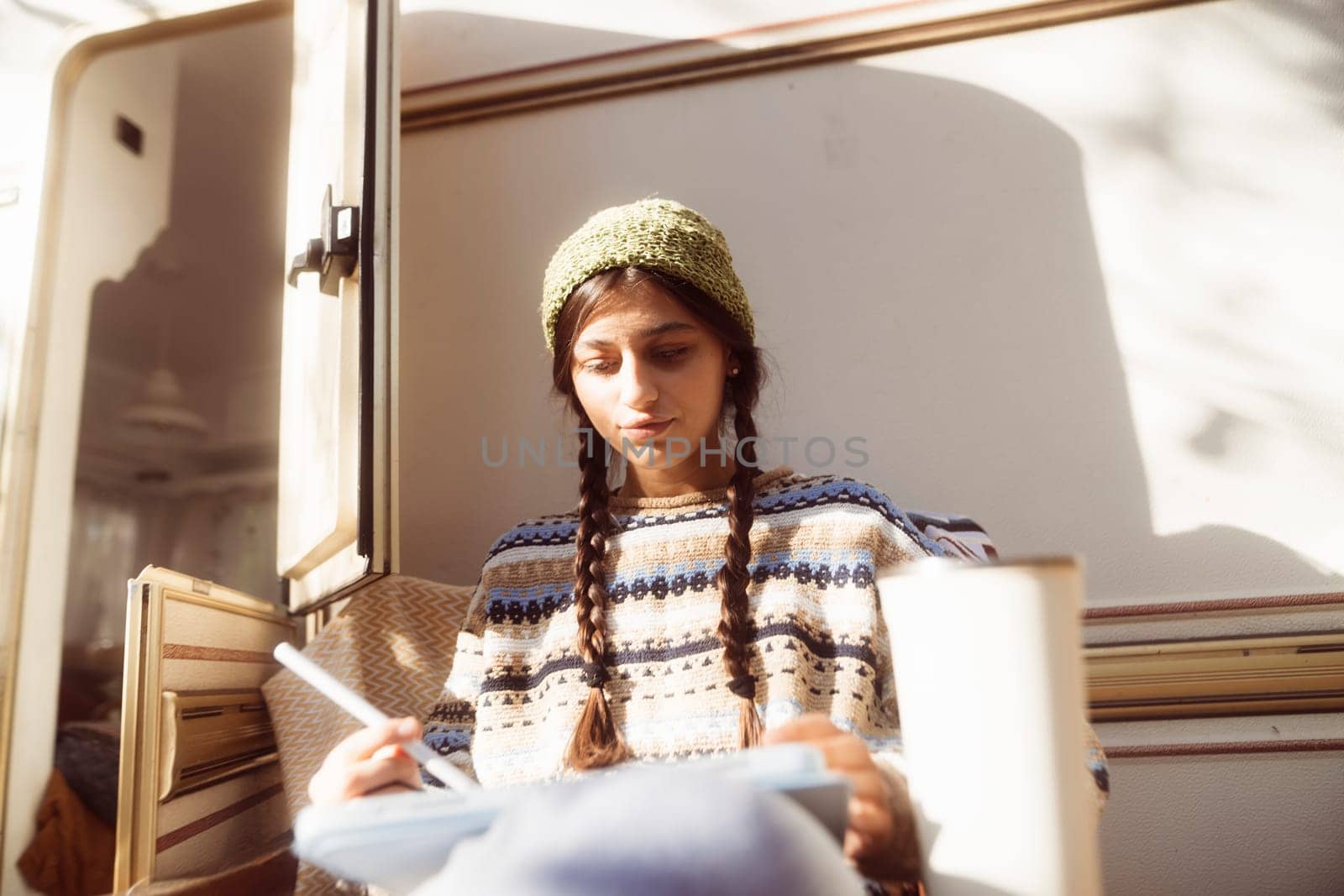 A stylish young woman rocks her hippie attire against the lush greenery of the park, with a trailer in sight. High quality photo