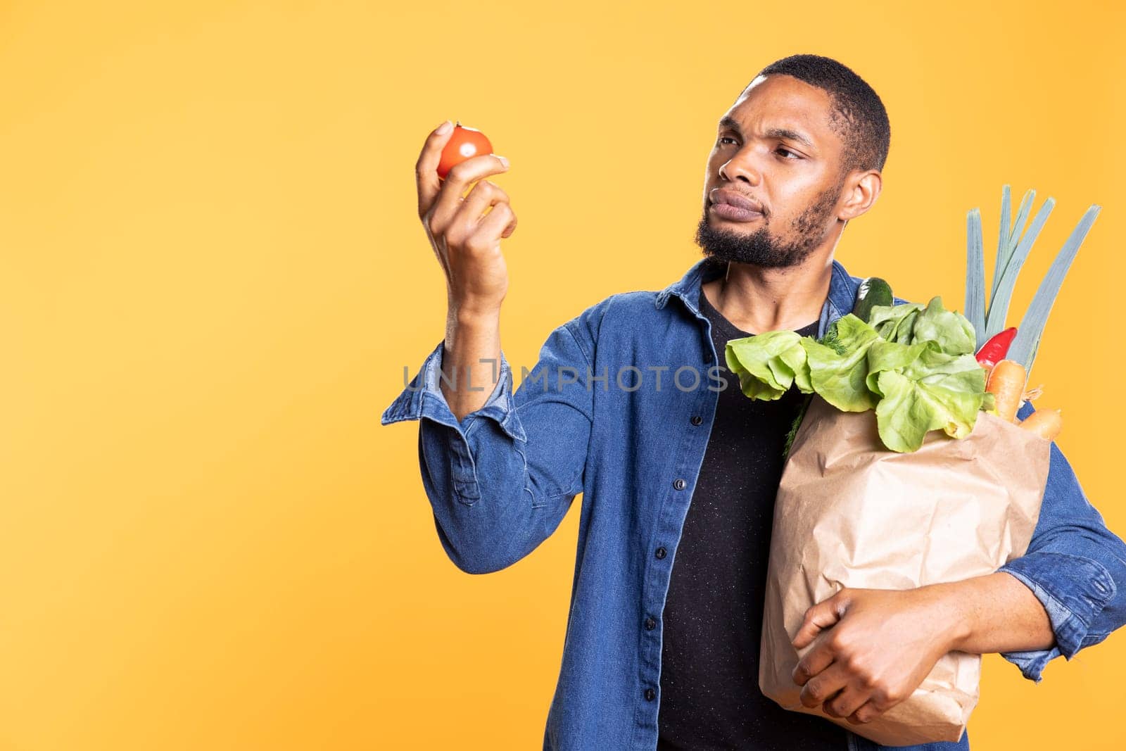 Vegan male person admiring a fresh ethically sourced tomato by DCStudio