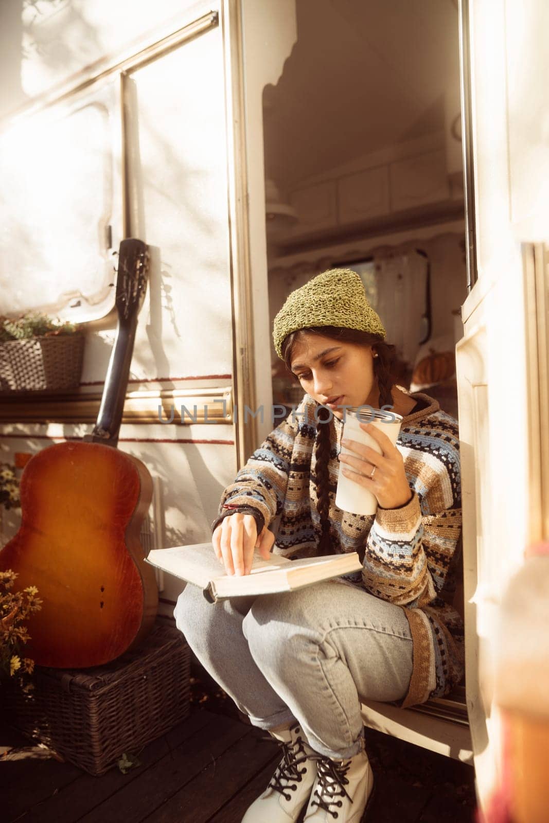 A stylish, bohemian lady, dressed in a hippie outfit, sips a warm beverage on the terrace. High quality photo