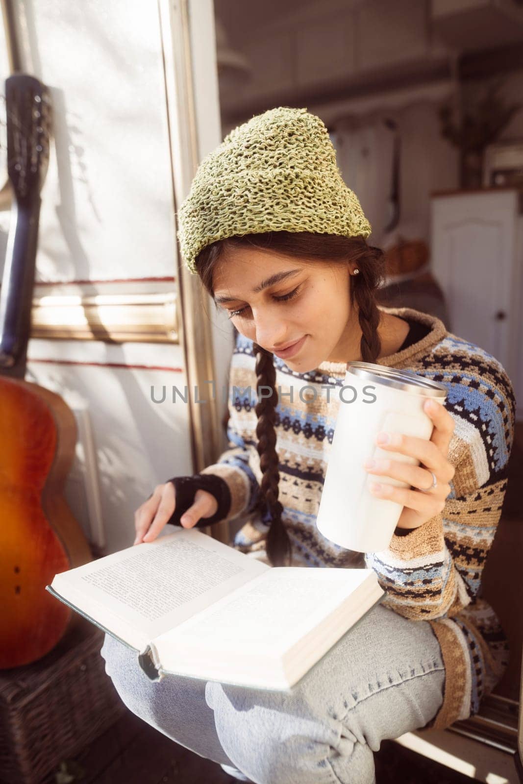 A chic, modern hippie woman indulges in a warm beverage on the terrace, exuding style. High quality photo