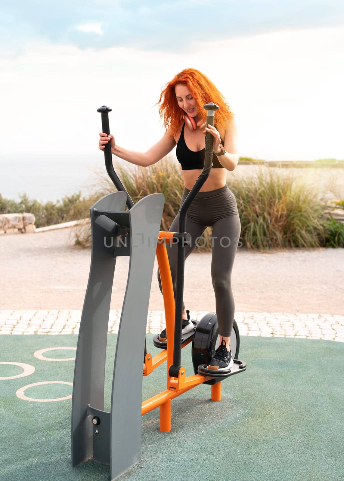 Happy woman athlete exercising at outdoor gym park by andreonegin