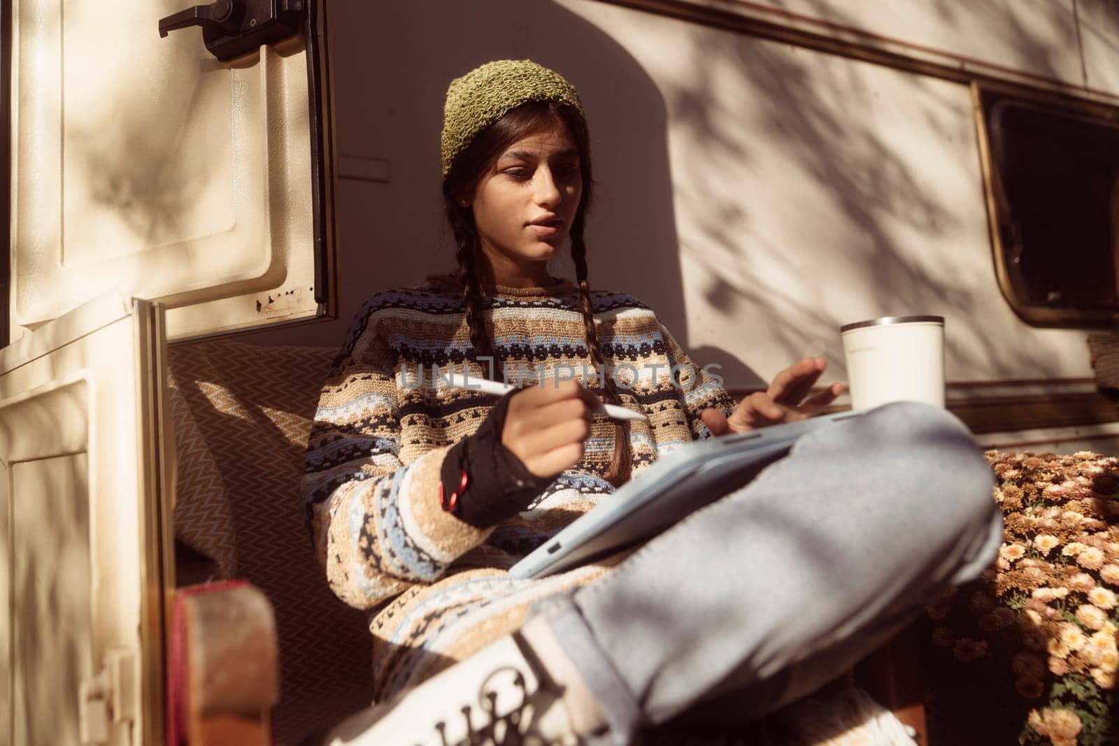 A captivating girl showcases her hippie-inspired look against the park landscape, with a trailer nearby. High quality photo