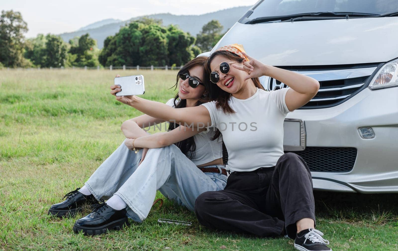 A young lesbian couple enjoyed driving out to see nature and taking picture together. by wichayada