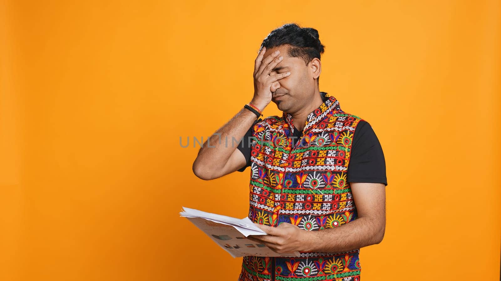 Irked manager looking over company financial profit report audit, disappointed by results, isolated over studio background. Mad indian man throwing business documents in frustration, camera B