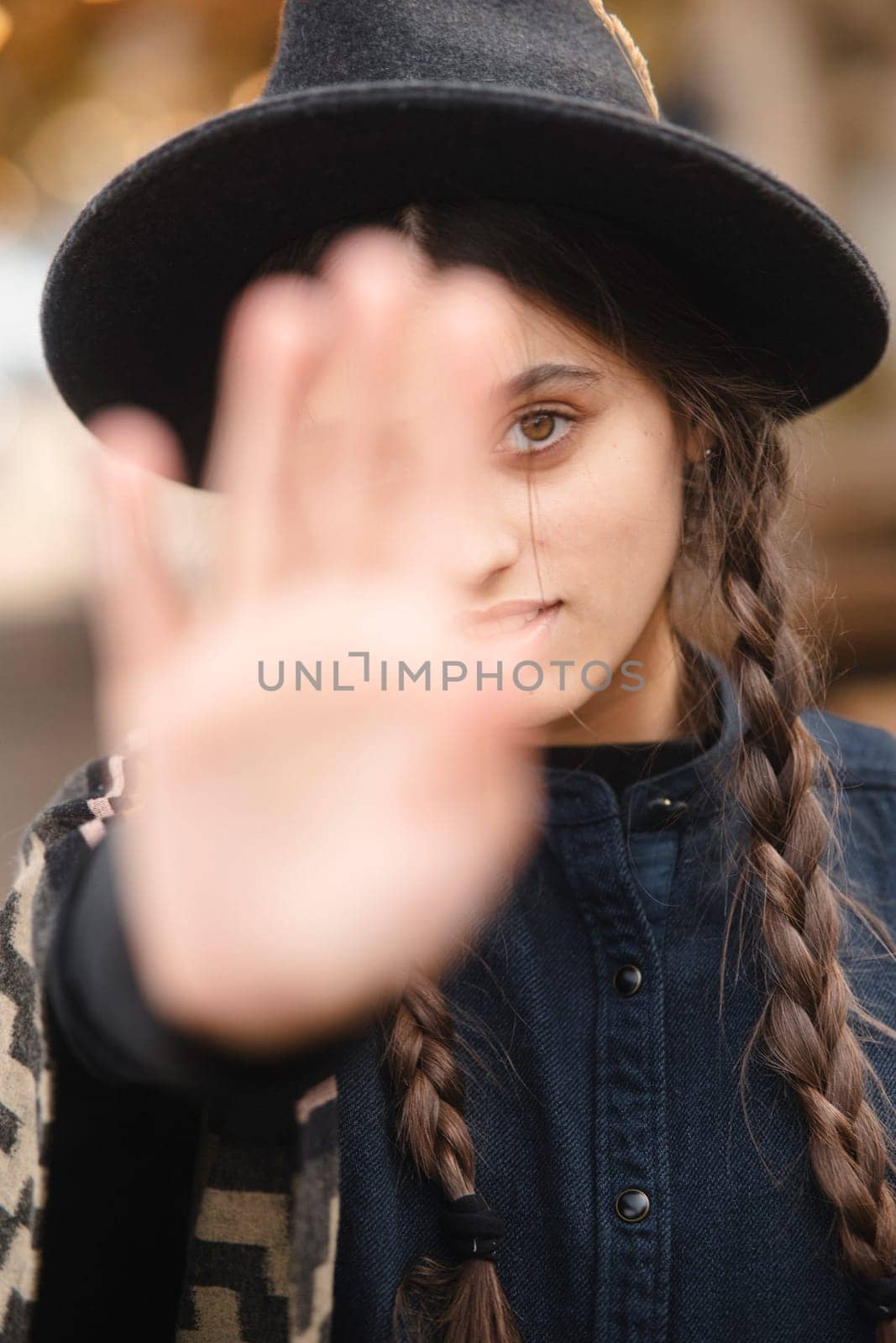 A stylish lady, embodying boho charm, dons a black hat while navigating the autumnal cityscape. by teksomolika