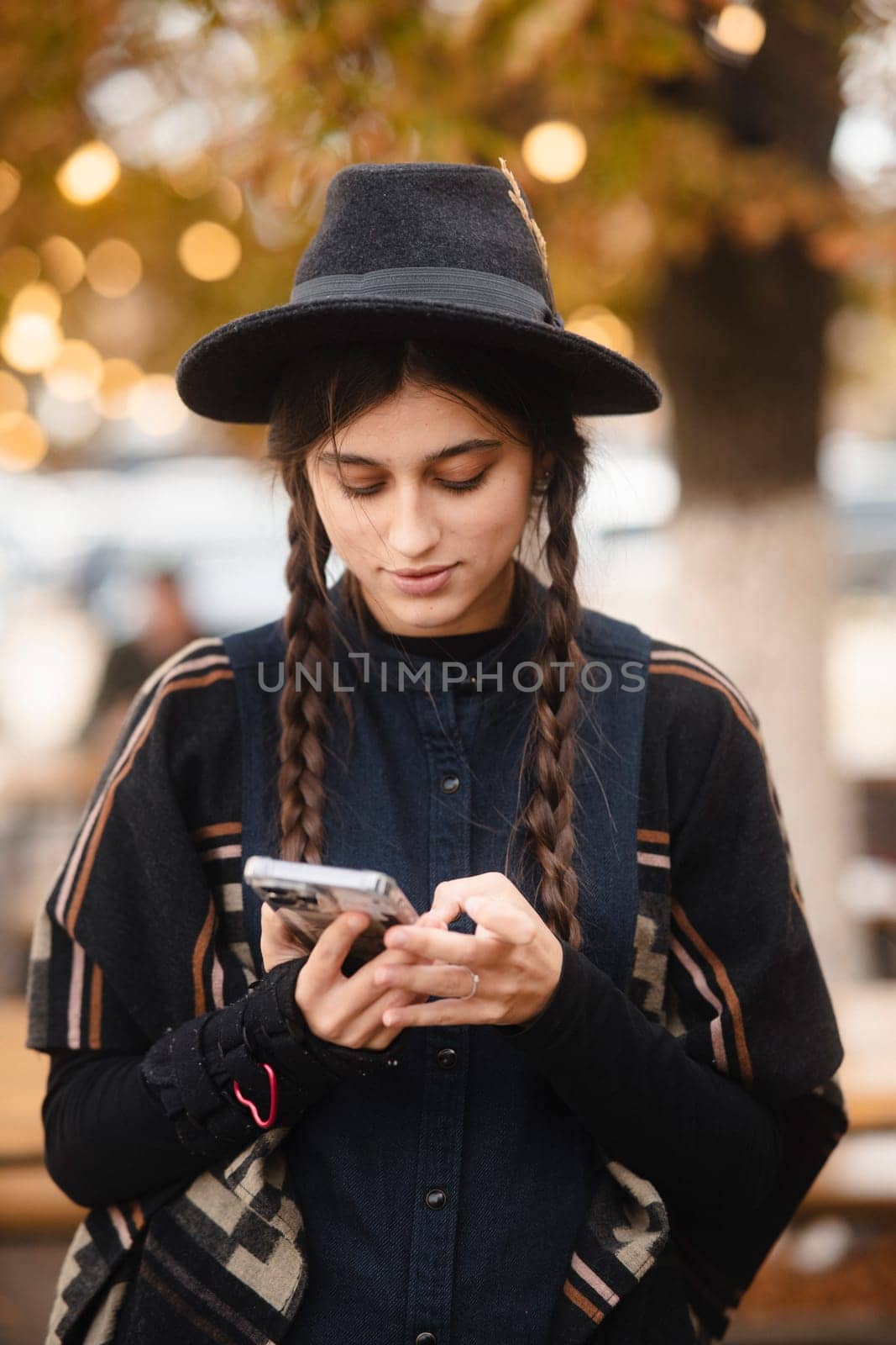 A stylish and radiant girl, wearing a black hat and a braided hairstyle. High quality photo